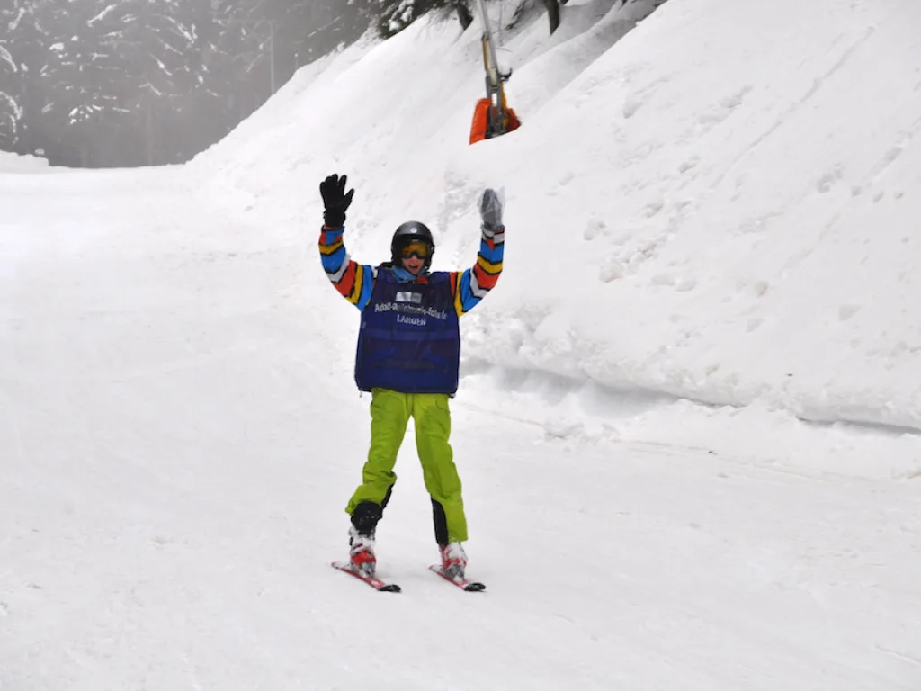 Person mit erhobenem Arm auf der Piste.